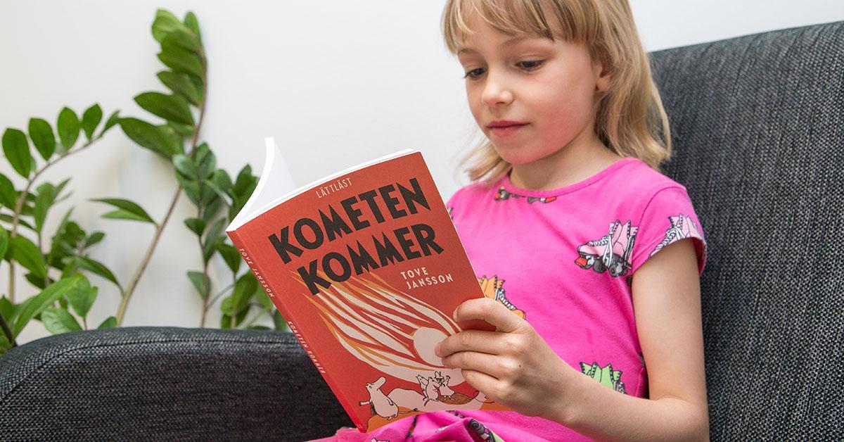 En flicka läser boken Kometen kommer.