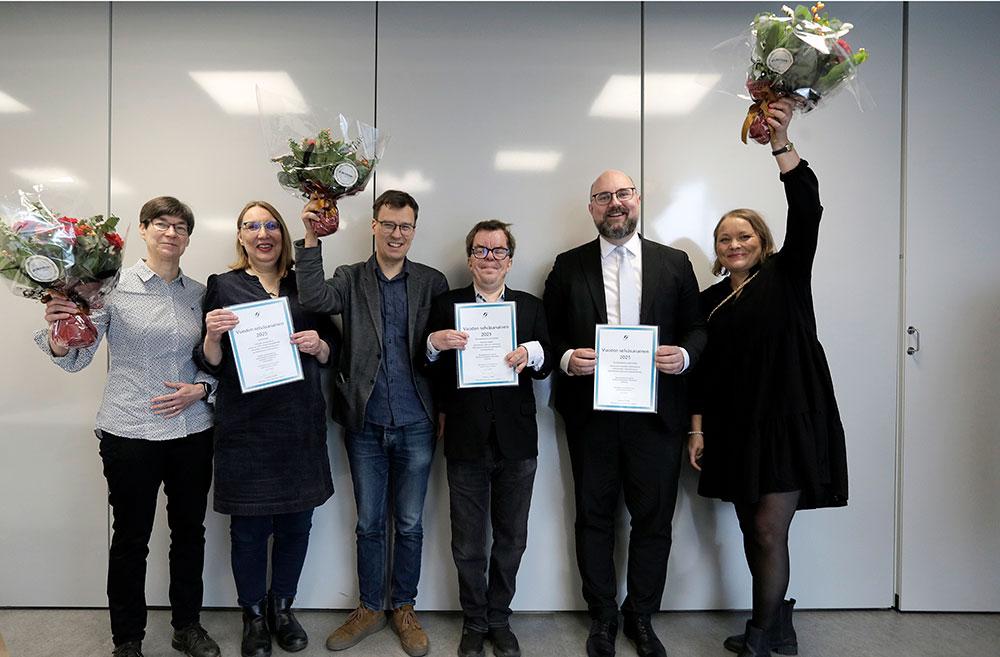 En grupp människor håller upp diplom och viftar med blommor.